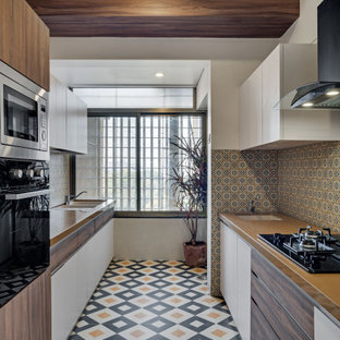 Design ideas for a large contemporary galley kitchen in Bengaluru with an undermount sink, flat-panel cabinets, white cabinets, wood benchtops, multi-coloured splashback, panelled appliances, porcelain floors, no island, multi-coloured floor and brown benchtop.