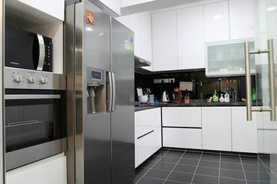シンガポールにある中くらいなモダンスタイルのおしゃれなキッチン (アンダーカウンターシンク、レイズドパネル扉のキャビネット、白いキャビネット、御影石カウンター、黒いキッチンパネル、ガラス板のキッチンパネル、シルバーの調理設備、セラミックタイルの床、アイランドなし) の写真