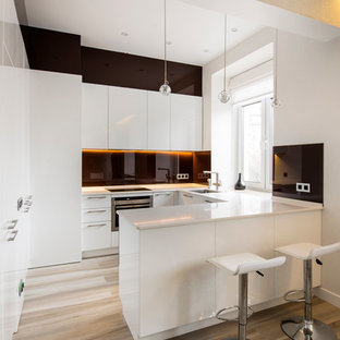 Idee per una piccola cucina moderna con ante lisce, ante bianche, paraspruzzi nero, pavimento in legno massello medio e penisola