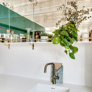 Photo of a large contemporary l-shaped open plan kitchen in Paris with green cabinets, no island, an integrated sink, flat-panel cabinets, white splashback, black appliances, light hardwood floors, brown floor and white benchtop.