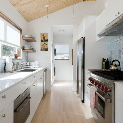 Enclosed kitchen - mid-sized scandinavian galley light wood floor enclosed kitchen idea in Los Angeles with a single-bowl sink, flat-panel cabinets, white cabinets, quartz countertops, blue backsplash, porcelain backsplash and stainless steel appliances