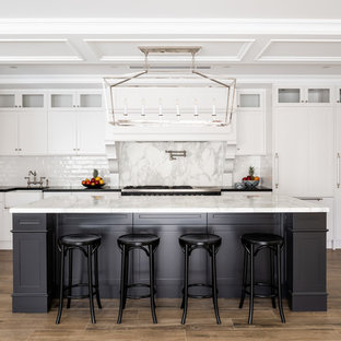 Inspiration for a traditional u-shaped eat-in kitchen in Perth with a farmhouse sink, recessed-panel cabinets, white cabinets, white splashback, medium hardwood floors, with island, brown floor and white benchtop.