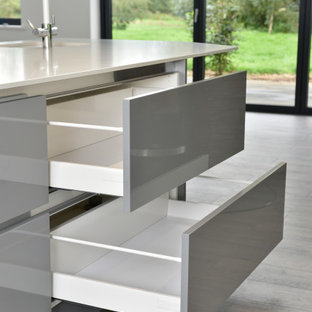 Offene, Einzeilige, Mittelgroße Moderne Küche mit Einbauwaschbecken, flächenbündigen Schrankfronten, lila Schränken, Mineralwerkstoff-Arbeitsplatte, Elektrogeräten mit Frontblende, braunem Holzboden, Kücheninsel, buntem Boden und weißer Arbeitsplatte in Cheshire