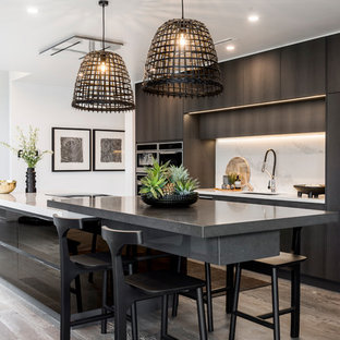 Design ideas for a contemporary galley kitchen in Gold Coast - Tweed with an undermount sink, flat-panel cabinets, black cabinets, white splashback, medium hardwood floors, with island, brown floor and white benchtop.