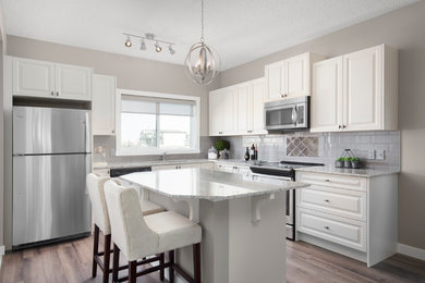 Open concept kitchen - mid-sized contemporary l-shaped medium tone wood floor open concept kitchen idea in Calgary with an undermount sink, raised-panel cabinets, white cabinets, granite countertops, gray backsplash, subway tile backsplash, stainless steel appliances and an island