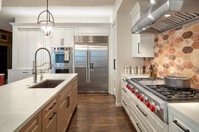 Inspiration for a large timeless medium tone wood floor and brown floor kitchen remodel in Dallas with a farmhouse sink, raised-panel cabinets, medium tone wood cabinets, quartz countertops, multicolored backsplash, cement tile backsplash, stainless steel appliances, two islands and white countertops