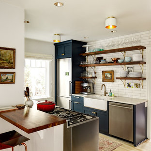 Photo of a country galley separate kitchen in Seattle with a farmhouse sink, open cabinets, blue cabinets, white splashback, stainless steel appliances, light hardwood floors and no island.