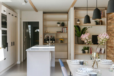 This is an example of a medium sized contemporary kitchen/diner in London with flat-panel cabinets, white cabinets, marble worktops, an island and grey floors.