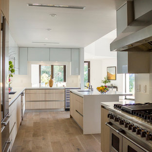 Inspiration for a large midcentury l-shaped open plan kitchen in Los Angeles with an integrated sink, flat-panel cabinets, light wood cabinets, laminate benchtops, stainless steel appliances, medium hardwood floors and with island.