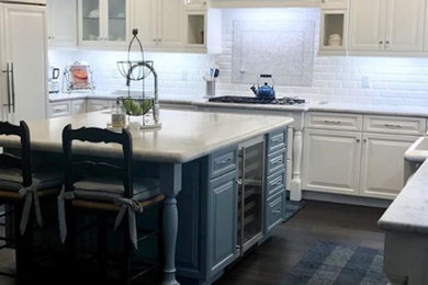 Example of a mid-sized french country l-shaped brown floor kitchen pantry design in Phoenix with flat-panel cabinets, white cabinets, marble countertops, white backsplash and white countertops