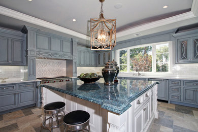 Large elegant u-shaped travertine floor eat-in kitchen photo in Los Angeles with a double-bowl sink, raised-panel cabinets, blue cabinets, granite countertops, white backsplash, subway tile backsplash, stainless steel appliances and an island