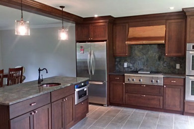 Amerikansk inredning av ett stort kök och matrum, med en undermonterad diskho, skåp i shakerstil, skåp i mellenmörkt trä, granitbänkskiva, rostfria vitvaror och en köksö