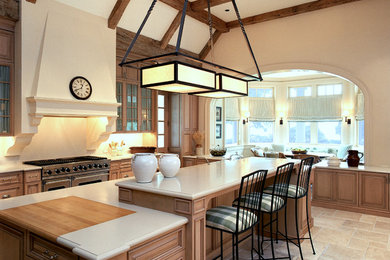 Inredning av ett klassiskt stort kök, med luckor med upphöjd panel, skåp i ljust trä, beige stänkskydd, rostfria vitvaror, kalkstensgolv och en köksö