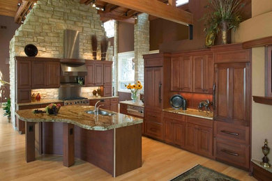 Design ideas for a traditional kitchen in Minneapolis with a submerged sink, raised-panel cabinets, dark wood cabinets, granite worktops, stainless steel appliances, light hardwood flooring and multiple islands.