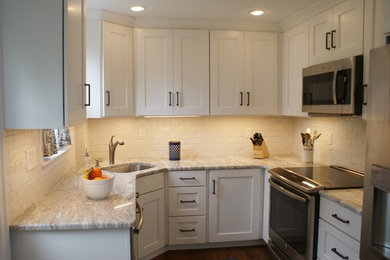 Inspiration for a small transitional u-shaped dark wood floor and brown floor kitchen remodel in Philadelphia with an undermount sink, shaker cabinets, white cabinets, marble countertops, white backsplash, subway tile backsplash and stainless steel appliances