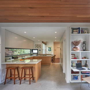 Photo of a mid-sized contemporary u-shaped kitchen in Melbourne with flat-panel cabinets, medium wood cabinets, window splashback, a peninsula, beige floor, a drop-in sink, panelled appliances and beige benchtop.