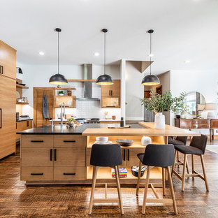 Scandinavian eat-in kitchen photos - Inspiration for a scandinavian dark wood floor and brown floor eat-in kitchen remodel in Dallas with light wood cabinets, white backsplash, an island, black countertops, flat-panel cabinets and paneled appliances