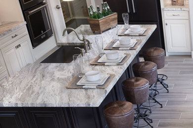 Eat-in kitchen - mid-sized transitional l-shaped porcelain tile and beige floor eat-in kitchen idea in Denver with a farmhouse sink, raised-panel cabinets, white cabinets, marble countertops, beige backsplash, glass tile backsplash, black appliances, an island and gray countertops