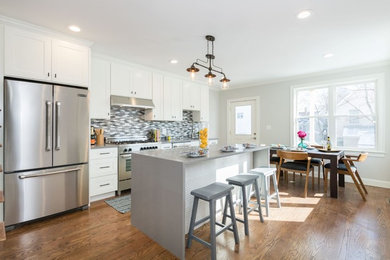 Eat-in kitchen - mid-sized contemporary single-wall medium tone wood floor and brown floor eat-in kitchen idea in Boston with an undermount sink, recessed-panel cabinets, white cabinets, quartz countertops, gray backsplash, mosaic tile backsplash, stainless steel appliances and an island