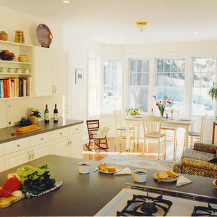 Photo of a large traditional l-shaped kitchen in Boston with a double-bowl sink, flat-panel cabinets, white cabinets, laminate benchtops, grey splashback, white appliances, ceramic floors and a peninsula.