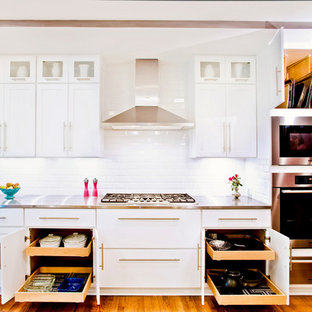 Foto di una cucina lineare tradizionale di medie dimensioni con ante in stile shaker, ante bianche, paraspruzzi bianco, paraspruzzi con piastrelle diamantate, elettrodomestici in acciaio inossidabile, top in acciaio inossidabile e pavimento in legno massello medio