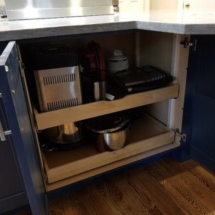 Mid-sized transitional l-shaped eat-in kitchen in DC Metro with an integrated sink, recessed-panel cabinets, medium wood cabinets, solid surface benchtops, blue splashback, mosaic tile splashback, stainless steel appliances, medium hardwood floors, a peninsula, brown floor and blue benchtop.