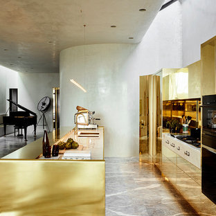 Photo of a contemporary galley open plan kitchen in Melbourne with an undermount sink, flat-panel cabinets, yellow cabinets, metallic splashback, metal splashback, black appliances, with island and grey floor.