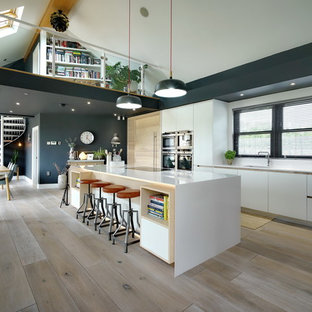 This is an example of a large contemporary single-wall open plan kitchen in Other with a submerged sink, flat-panel cabinets, white cabinets, light hardwood flooring, an island, beige floors and white splashback.