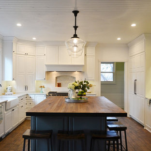 Exemple d'une grand cuisine américaine tendance en U avec un évier de ferme, des portes de placard blanches, un plan de travail en bois, une crédence blanche, une crédence en carreau de céramique, un électroménager blanc, un sol en bois foncé, un îlot central, un sol marron et un plan de travail rouge.