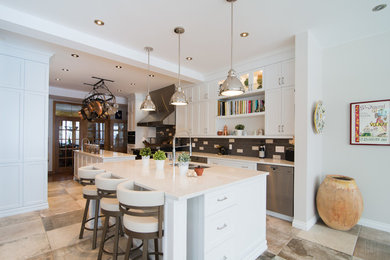 Large transitional ceramic tile kitchen photo in Montreal with a double-bowl sink, shaker cabinets, white cabinets, quartz countertops, gray backsplash, ceramic backsplash, stainless steel appliances and two islands