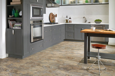 Eat-in kitchen - mid-sized modern l-shaped laminate floor eat-in kitchen idea in Other with a drop-in sink, shaker cabinets, gray cabinets, white backsplash, subway tile backsplash, stainless steel appliances and an island