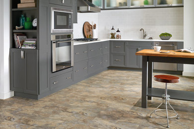 Ejemplo de cocina clásica renovada con armarios estilo shaker, puertas de armario grises, salpicadero blanco, salpicadero de azulejos tipo metro y electrodomésticos de acero inoxidable