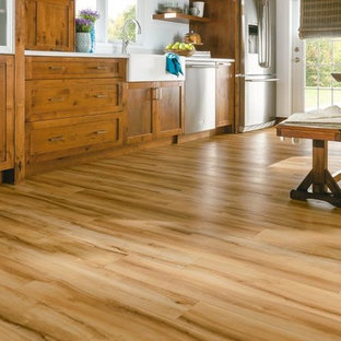 This is an example of a large country single-wall eat-in kitchen in Orlando with a farmhouse sink, shaker cabinets, medium wood cabinets, stainless steel appliances and vinyl floors.