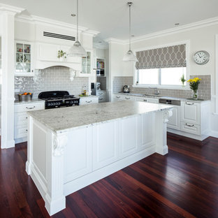 Photo of a mid-sized traditional l-shaped kitchen in Brisbane with an undermount sink, white cabinets, marble benchtops, cement tile splashback, black appliances, dark hardwood floors, with island, raised-panel cabinets, grey splashback, brown floor and grey benchtop.