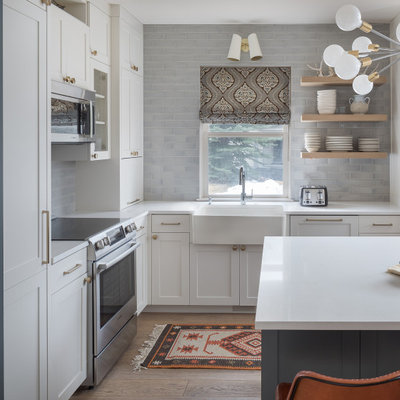 Inspiration for a small transitional l-shaped medium tone wood floor and beige floor open concept kitchen remodel in Denver with a farmhouse sink, shaker cabinets, gray cabinets, quartz countertops, gray backsplash, subway tile backsplash, stainless steel appliances, an island and white countertops