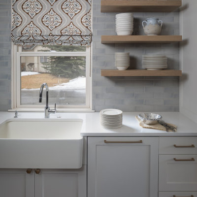 Example of a small transitional l-shaped brown floor and medium tone wood floor open concept kitchen design in Denver with a farmhouse sink, shaker cabinets, gray cabinets, quartz countertops, gray backsplash, subway tile backsplash, stainless steel appliances, an island and white countertops