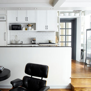 Small industrial open concept kitchen photos - Open concept kitchen - small industrial u-shaped medium tone wood floor open concept kitchen idea in New York with recessed-panel cabinets, white cabinets, white backsplash, subway tile backsplash, stainless steel appliances, an undermount sink, quartz countertops and a peninsula