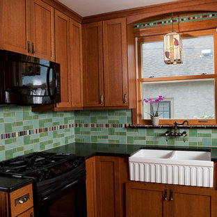Small traditional enclosed kitchen ideas - Example of a small classic u-shaped enclosed kitchen design in Minneapolis with a farmhouse sink, shaker cabinets, dark wood cabinets, solid surface countertops, green backsplash, cement tile backsplash, black appliances and no island