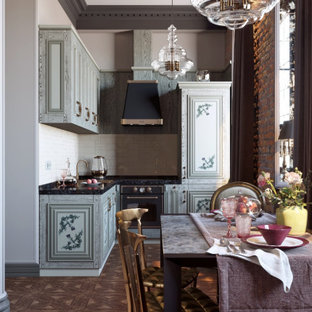 Victorian l-shaped kitchen/diner in London with raised-panel cabinets, grey cabinets, black appliances, dark hardwood flooring, brown floors and black worktops.
