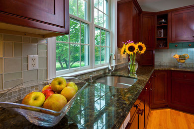 Example of an arts and crafts l-shaped light wood floor eat-in kitchen design in Newark with an undermount sink, shaker cabinets, medium tone wood cabinets, granite countertops, green backsplash and glass tile backsplash