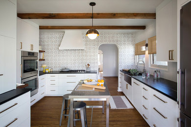Eat-in kitchen - mid-sized modern light wood floor eat-in kitchen idea in San Diego with a farmhouse sink, flat-panel cabinets, white cabinets, quartzite countertops, black backsplash, ceramic backsplash, stainless steel appliances and no island