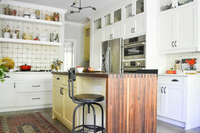 Eat-in kitchen - mid-sized traditional l-shaped eat-in kitchen idea with a farmhouse sink, shaker cabinets, white cabinets, wood countertops, multicolored backsplash, ceramic backsplash, stainless steel appliances, an island and brown countertops