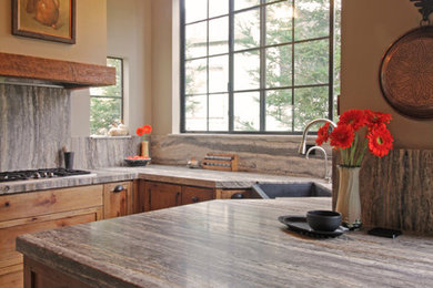 Example of a cottage u-shaped light wood floor kitchen design in San Francisco with a farmhouse sink, shaker cabinets, medium tone wood cabinets, stone slab backsplash and a peninsula