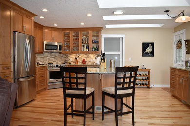 Example of a mid-sized arts and crafts u-shaped light wood floor and brown floor open concept kitchen design in Other with an undermount sink, shaker cabinets, medium tone wood cabinets, quartz countertops, brown backsplash, stone tile backsplash, stainless steel appliances, an island and multicolored countertops