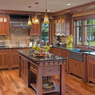 Large craftsman eat-in kitchen designs - Large arts and crafts u-shaped dark wood floor eat-in kitchen photo in Milwaukee with a farmhouse sink, recessed-panel cabinets, medium tone wood cabinets, granite countertops, brown backsplash, stone tile backsplash, paneled appliances and two islands