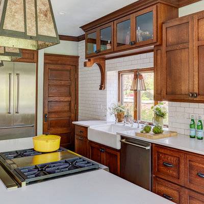 Mid-sized arts and crafts medium tone wood floor and brown floor kitchen photo in Milwaukee with a farmhouse sink, shaker cabinets, medium tone wood cabinets, quartz countertops, white backsplash, subway tile backsplash, stainless steel appliances, an island and white countertops