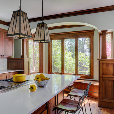 Inspiration for a mid-sized craftsman medium tone wood floor and brown floor kitchen remodel in Milwaukee with a farmhouse sink, shaker cabinets, medium tone wood cabinets, quartz countertops, white backsplash, subway tile backsplash, stainless steel appliances, an island and white countertops