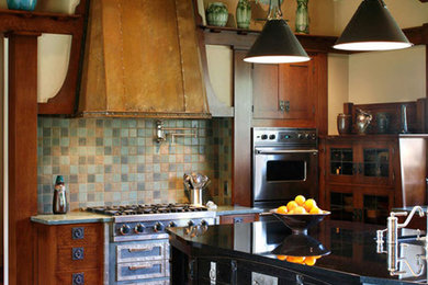 サンタバーバラにあるラスティックスタイルのおしゃれなキッチン (濃色木目調キャビネット、緑のキッチンパネル、シルバーの調理設備、スレートのキッチンパネル) の写真