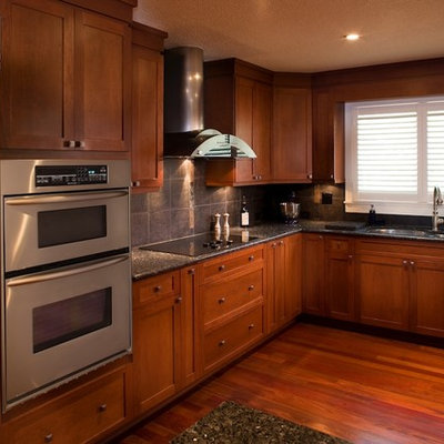 Inspiration for a mid-sized craftsman single-wall medium tone wood floor eat-in kitchen remodel in Tampa with a double-bowl sink, recessed-panel cabinets, medium tone wood cabinets, granite countertops, black backsplash, ceramic backsplash, stainless steel appliances and an island