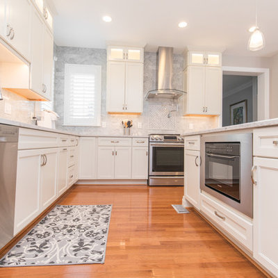 Mid-sized elegant l-shaped medium tone wood floor and brown floor eat-in kitchen photo in DC Metro with an undermount sink, recessed-panel cabinets, white cabinets, marble countertops, gray backsplash, marble backsplash, stainless steel appliances and an island